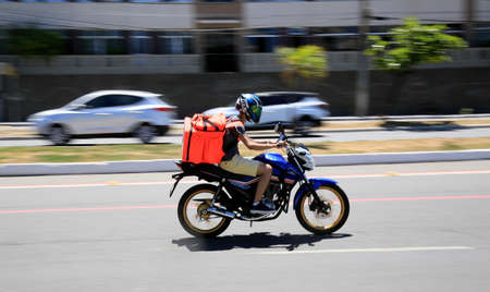 salvador, bahia, brazil - january 6, 2021: food delivery man by application is seen riding a motorcycle on the street in the Pituba neighborhood in the city of Salvador.のeditorial素材