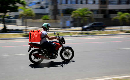 salvador, bahia, brazil - january 6, 2021: food delivery man by application is seen riding a motorcycle on the street in the Pituba neighborhood in the city of Salvador.のeditorial素材