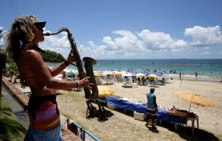salvador, bahia / brazil - january 31, 2019: woman is seen playing the saxophone on the Nossa Senhora de Gaudalupe beach in Ilha dos Frades, in the city of Salvador.のeditorial素材