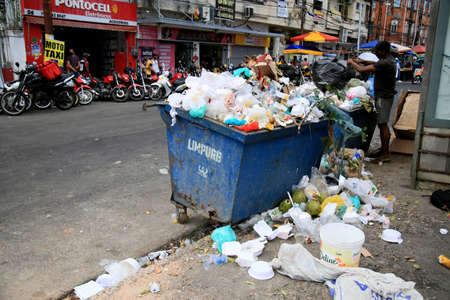 salvador, bahia, brazil - december 16, 2020: man turns over garbage container in search of material for recycling in downtown Salvador.のeditorial素材