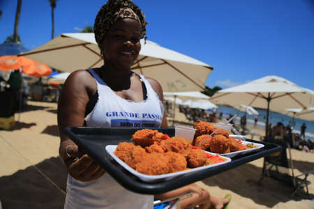 salvador, bahia / brazil - December 30, 2015: Andreia Pinheiro, from Bahia de Acaraje, prepares the food on a sales board at Itapua Beach in Salvador.のeditorial素材