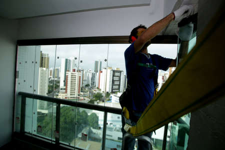 salvador, bahia / brazil - may 17, 2017: worker is seen wearing a seat belt during installation of glassware in a high and dangerous place.のeditorial素材