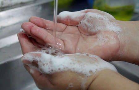 person washing hands in kitchen sink in the city of Salvador.の写真素材