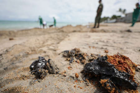 vera cruz, bahia / brazil - October 18, 2019: Young woman observes oil macha at Praia do Sol, the place was affected by oil spill at sea.のeditorial素材