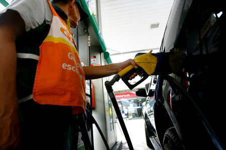 salvador, bahia / brazil - october 8, 2014: gas station attendant is seen filling up a vehicle at petrol stations in the Petrobras network, in the city of Salvador.のeditorial素材