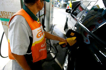 salvador, bahia / brazil - october 8, 2014: gas station attendant is seen filling up a vehicle at petrol stations in the Petrobras network, in the city of Salvador.のeditorial素材