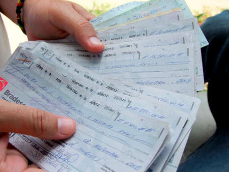 eunapolis, bahia / brazil - december 18, 2009: hands hold bottomless check sheets from Bradesco bank.のeditorial素材