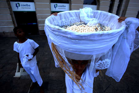 salvador, bahia / brazil - august 15, 2018: Young Candomble supporter carries the basket of popcorn in reference to the orixa Omolu, in Pelourinho in Salvador.のeditorial素材