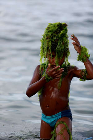 salvador, bahia / brazil - february 2, 2015: child plays with algae on the Rio Vermelho beach in the city of Salvador.のeditorial素材