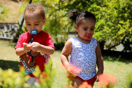 salvador, bahia / brazil - june5, 2019: children are seen with pacifiers in their mouths while playing in a garden in the city of Salvador.のeditorial素材