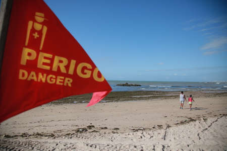 salvador, bahia / brazil - November 7, 2019: Red flag stuck in the sand of Itapua beach warns bathers of dangerous place with risk of drowning.のeditorial素材