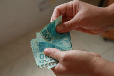 salvador, bahia, brazil - october 4, 2021: hand counting Real banknotes, Brazilian currency.のeditorial素材