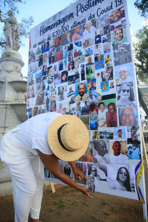 salvador, bahia, brazil - January 13, 2022: woman pastes photos of Covid-19 victims during tribute to 620,000 people killed by the disease in Brazil.のeditorial素材