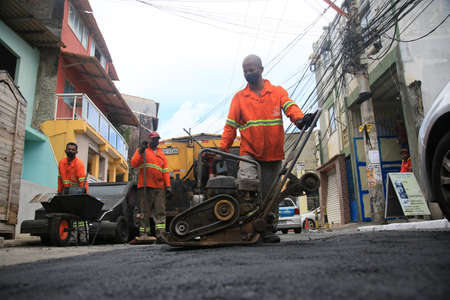Salvador, Bahia, Brazil - February 18, 2022: Workers repair a hole in the asphalt of a street in the city of Salvador.のeditorial素材