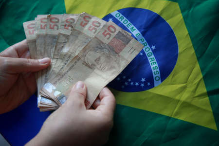 salvador, bahia, brazil - april 3, 2022: fifty reais banknotes next to a brazil flag.の写真素材