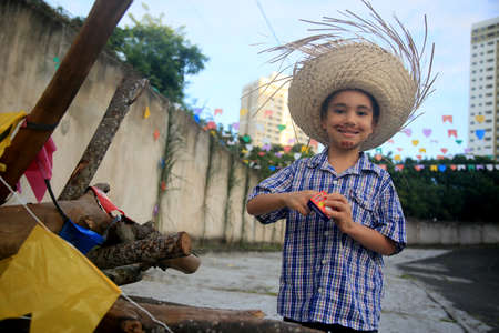 Salvador, Bahia, Brazil - June 22, 2022: Child wearing straw hat and releasing fireworks during SÃ£o JoÃ£o party in Salvador city.のeditorial素材