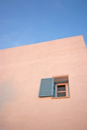 Vintage blue windows on the white wall and blue sky 