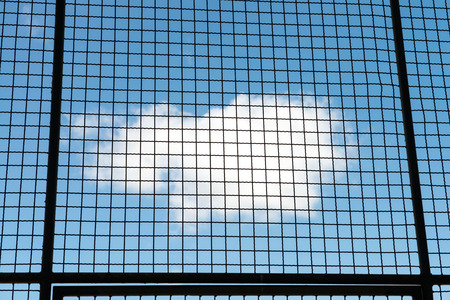 Metal mesh wire fence with blue sky and cloud background の写真素材