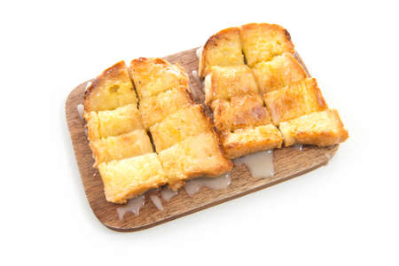Bread toast and condensed milk on wooden plate over white backgroundの写真素材