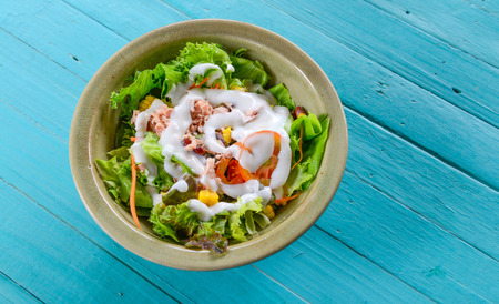 vegetable salad with tuna in a bowl on blue tableの写真素材