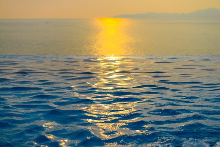 Beautiful view of Infinity Swimming Pool with sunset on the sea at twilight times.の写真素材