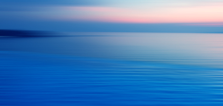 Blurred background of refraction in water. Panoramic dramatic view of Infinity Swimming Pool with sunset on the sea at twilight times.の写真素材