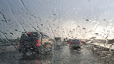 Inside the car. Closeup rain water drops. car windshield view during rainy day on highway in the eveningの写真素材