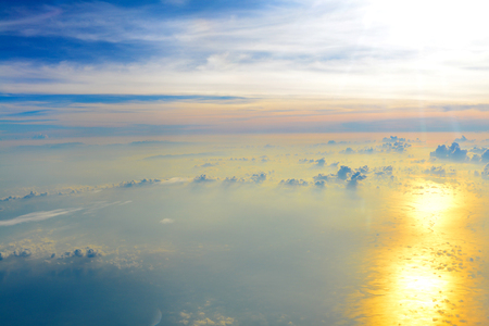 Beautiful view, Sun rise in the morning of blue sky above the white clouds and land background with golden light looking through an airplane window, Vacation timeの写真素材