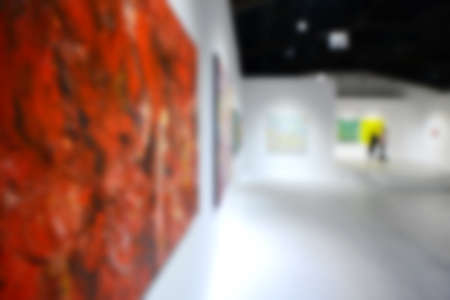 People looking at paintings on white wall in Art exhibition gallery. Blurry background.の写真素材