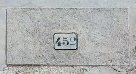 House number 452 sign fixed to old white wall.の写真素材