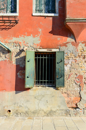 Green window on orange old house wall Cracks in concrete visible red bricks in Venice, Italy.の写真素材