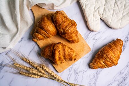 freshly baked croissants on wooden cutting board.の写真素材