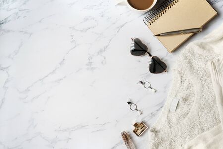 White sweater, women accessories,coffee ,notebook, smart phone on marble background top view. Women clothing. Flat layの写真素材