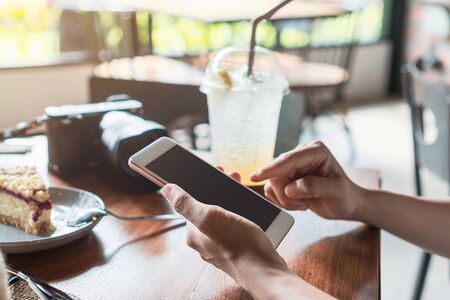 Close up of women's hands holding mobile phone in cafe.