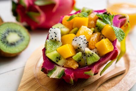 tropical fruits salad served in a half of  dragon fruitの写真素材