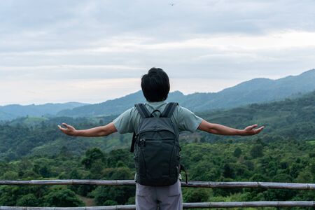 Man relaxing on top of a mountain and enjoying the view of sunsetの写真素材