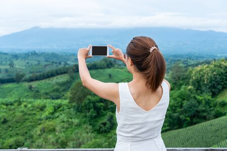 Woman relaxing on top of a mountain and enjoying the view of sunsetの写真素材