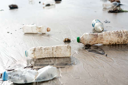 Plastic bottles and other trash abandoned on the beach. Environmental pollution, Ecological problem concept. Close upの写真素材