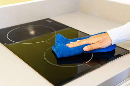 Close up of hand cleaning electric stove surface with a rag. Home, housekeeping concept.の写真素材