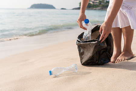 Volunteer woman collecting garbage on the beach. Ecology conceptの写真素材