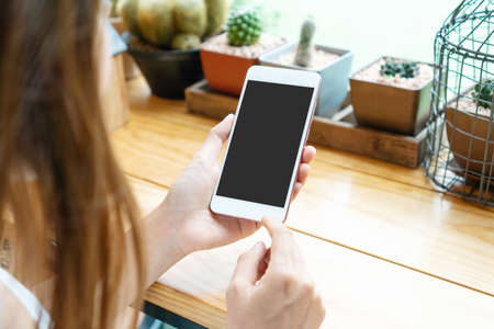 Hands of Asian woman using smartphone on wooden table in cafe.の写真素材