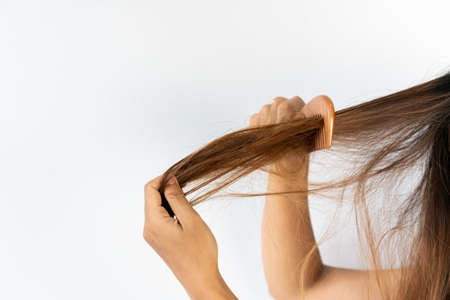 Close up of sad young Asian girl with her damaged and hangled hair. Isolated on white background, copy spaceの写真素材