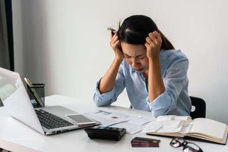Stressed Asian woman working at her workplace. Business concept. Close up