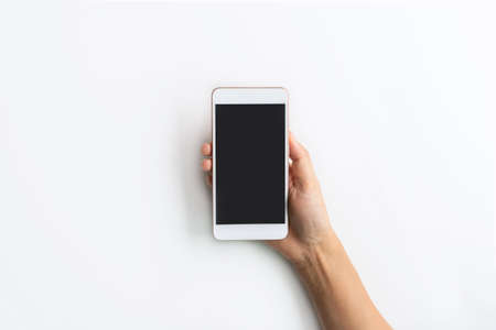 Top view studio shot hand holding smartphone blank touch screen. Isolated on white background. Copy spaceの写真素材