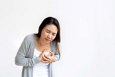 Portrait of tired young woman feeling pain ache touching chest having heart attack.Isolated on white background, infarction or female heart disease concept. Copy spaceの写真素材