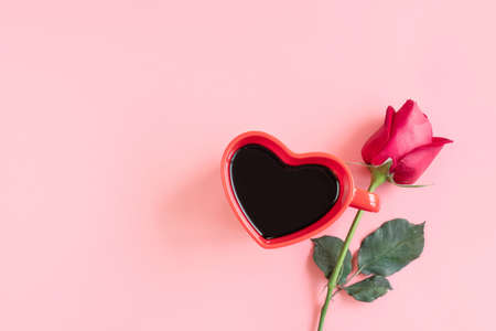 Valentine's Day background. Heart shaped cup of black coffee and rose on pastel pink background. Valentines day concept. Flat lay, top view, copy spaceの写真素材