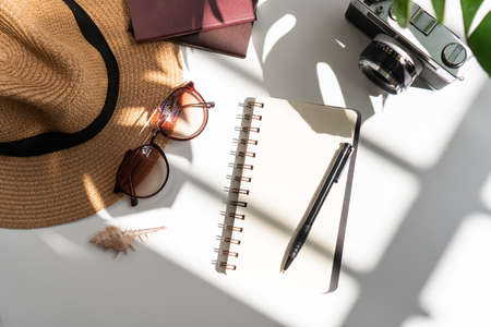 Flat lay of summer items with green tropical leaf shadow on white desk. Summer, holiday and planning travel concepts. top view and copy space.の写真素材