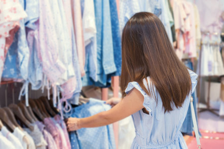 Beautiful young Asian woman in blue dress shopping fashion cloths in department store, blur background. Shopping conceptの写真素材