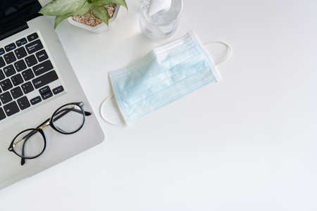 Top view of medical face mask and hand sanitizer on desk in office during the virus crisis. Working from home, business and health care, new normal lifestyle concept.の写真素材