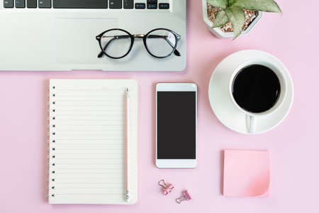 Flat lay of mobile phone, a cup of coffee, laptop and stationary of student on pink table. Business...
